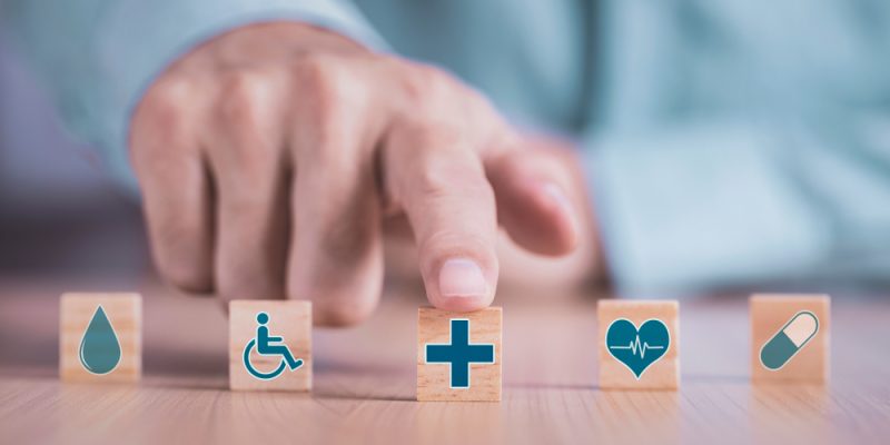 Businessman,Chooses,A,Emoticon,Icons,Healthcare,Medical,Symbol,On,Wooden